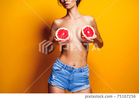 Crop woman holding grapefruit near breasts Crop woman holding grapefruit near breasts 75107256
