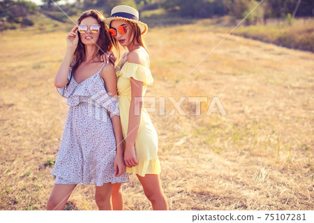 two pretty girlfriends in summer dresses two pretty girlfriends in summer dresses 75107281