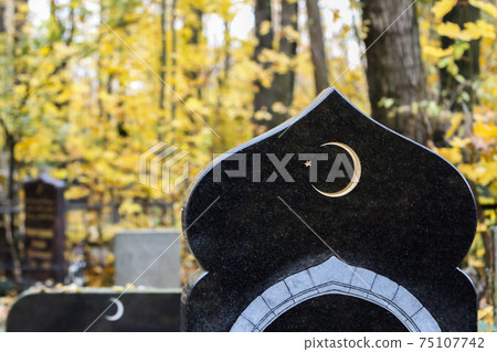 Muslim crescent moon with a star on a dark marble gravestone. Waxing moon Islamic symbol on Muslim graveyard 75107742