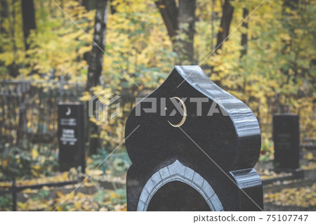 Old islamic cemetery, funeral and burial of muslim. A grave with a stone with crescent moon. Black gravestone Old islamic cemetery, funeral and burial of muslim. A grave with a stone with crescent moon. Black gravestone 75107747