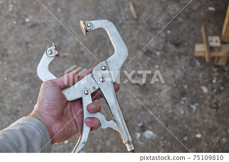 Male Craftsman Holding C-Clamp Locking Pliers in the Construction Site 75109810