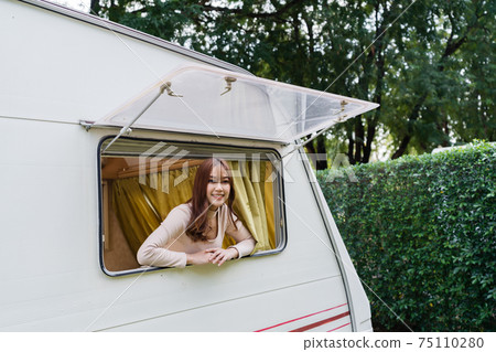 happy woman at window of a camper RV van motorhome happy woman at window of a camper RV van motorhome 75110280