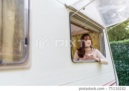happy woman drinking coffee at window of a camper RV van motorhome happy woman drinking coffee at window of a camper RV van motorhome 75110282