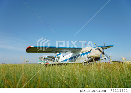 Propeller plane in green field. Warm summer photo 75111531