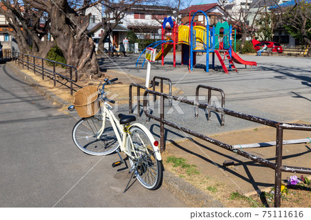 A fashionable white bicycle that a person who came to a park in a residential area got on 75111616