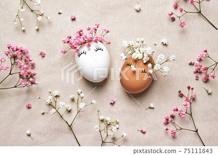 White and black Easter eggs with natural flowers wreath on linen background. Zero Waste Easter Concept. Racial Equality symbol 75111843