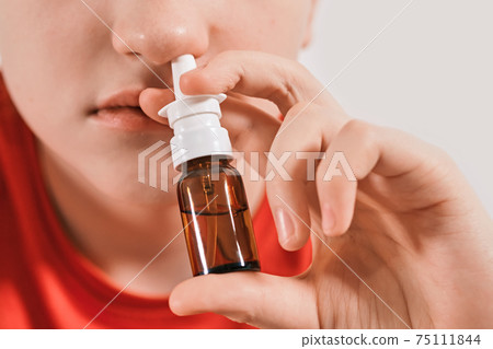 Blond Boy drips nose drops from runny nose. Treatment of colds and allergic rhinitis. Selective focus Blond Boy drips nose drops from runny nose. Treatment of colds and allergic rhinitis. Selective focus 75111844