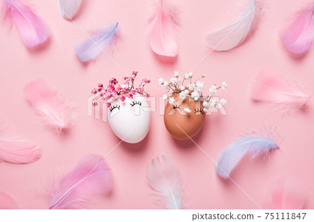 White and black Easter eggs with natural flowers wreath on soft pink feathers background. Zero Waste Easter Concept. Racial Equality symbol White and black Easter eggs with natural flowers wreath on soft pink feathers background. Zero Waste Easter Concept. Racial Equality symbol 75111847