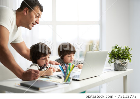 Entertaining kids. Little latin boys drawing pictures during online lesson for kids. Father spending time together with his children at home Entertaining kids. Little latin boys drawing pictures during online lesson for kids. Father spending time together with his children at home 75112772