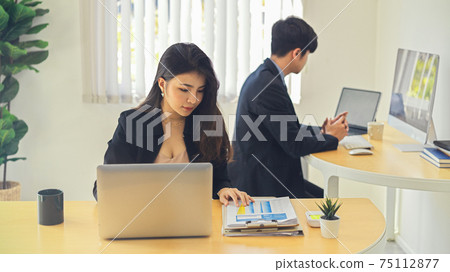 Two businesspeople working on their work with office supplies in office room Two businesspeople working on their work with office supplies in office room 75112877