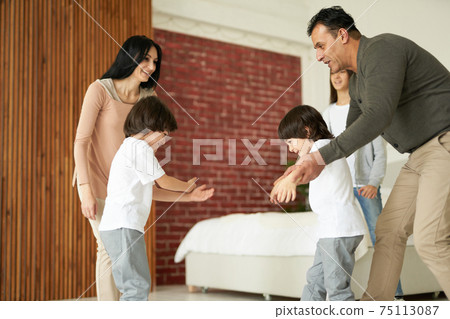 Joyful latin children, little twin boys smiling while having fun with their sister and parents indoors. Mom and dad playing with their kids at home Joyful latin children, little twin boys smiling while having fun with their sister and parents indoors. Mom and dad playing with their kids at home 75113087