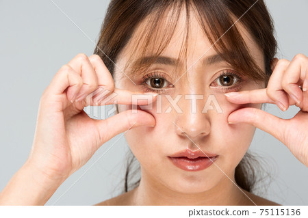 Woman pinching the lower eyelid Woman pinching the lower eyelid 75115136