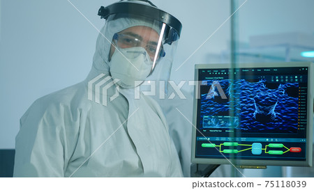 Microbiologist in ppe suit standing in laboratory looking at camera Microbiologist in ppe suit standing in laboratory looking at camera 75118039