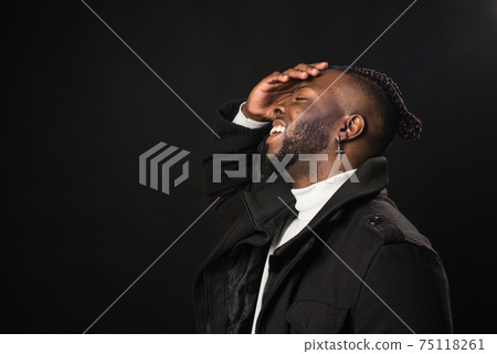 Black man in profile laughing with his hand on his face. Black man in profile laughing with his hand on his face. 75118261