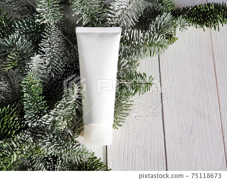 Unbranded white cosmetic products squeeze tube - cream, moisturizer, facial cleanser or shampoo on white wooden background with snowy branches of christmas fir tree. Mockup, template, copy space 75118673