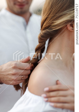 Close-up the guy braids the girl's braid 75119717