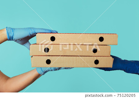 Getting pizza delivery. Man employee in gloves giving carton boxes to the woman. Getting pizza delivery. Man employee in gloves giving carton boxes to the woman. 75120205