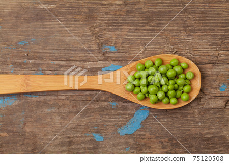 Green peas in spoon on wooden board background 75120508