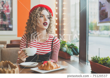 Young nice woman drinking coffee in cafeteria 75120537