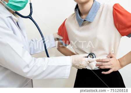 Asian child girl with flatulence,bloated stomach checking the abdomen,physical examination,doctor using a stethoscope,listen to the sound of bowel movement,indigestion,pain illness,abdominal problems 75120818
