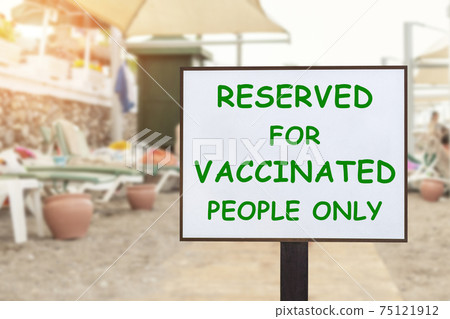 Text plate RESERVED FOR VACCINATED PEOPLE ONLY at luxury hotel sea beach resort area empty loungers on summer day. New normal travel and vacation concept. Covid-19 pandemic restriction and limit Text plate RESERVED FOR VACCINATED PEOPLE ONLY at luxury hotel sea beach resort area empty loungers on summer day. New normal travel and vacation concept. Covid-19 pandemic restriction and limit 75121912