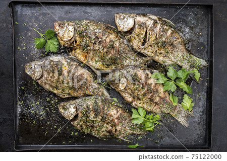 raditional barbecue crucian carp with herbs offered as top view on an old rustic metal tray 75122000