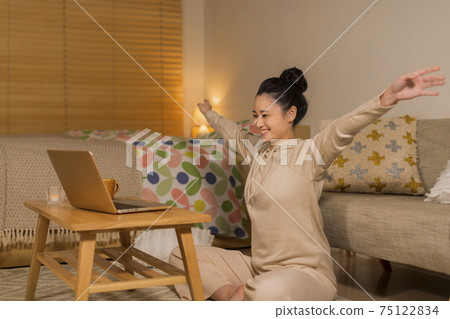 A woman stretching while looking at a computer A woman stretching while looking at a computer 75122834