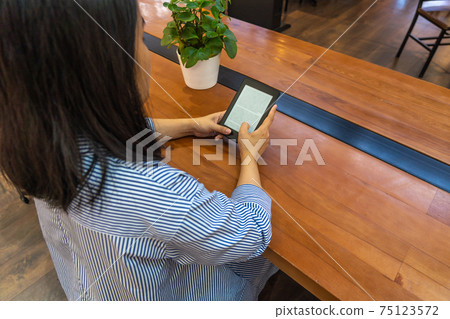 Student reading ebook from tablet holding on hands 75123572