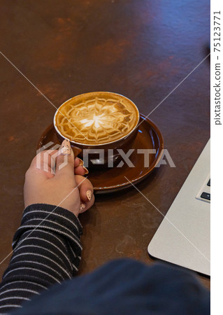 Woman hand with beautiful nails holding a cup of latte Woman hand with beautiful nails holding a cup of latte 75123771