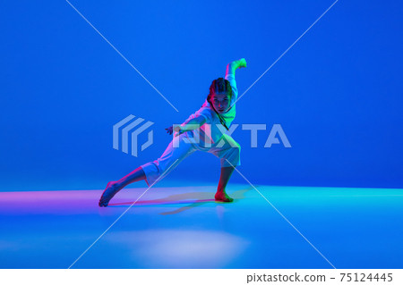 Young girl dancing hip-hop in white attire on colorful background in neon light 75124445