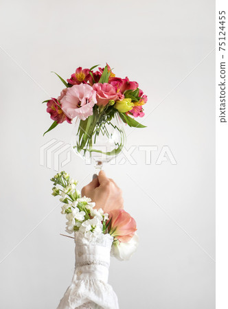 Wine glass full of fresh Spring flowers in female Wine glass full of fresh Spring flowers in female 75124455