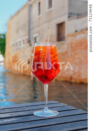 Glass of refreshing Aperol Spritz cocktail served on the deck bar in Venice. Glass of refreshing Aperol Spritz cocktail served on the deck bar in Venice. 75124648
