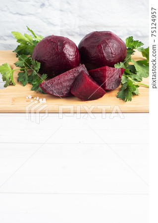 Boiled beets whole and cut on a cutting Board with parsley leaves on a white background. Copy space 75124957