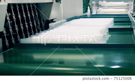 Factory worker wrapping many plastic cups 75125006
