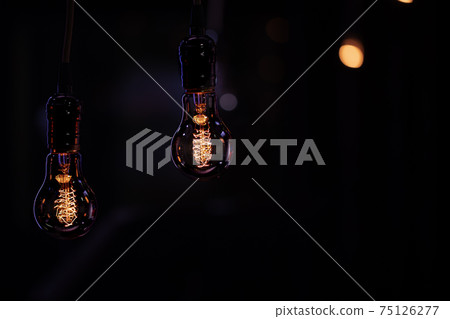 Two burning lamps on a blurred dark background. 75126277
