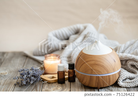 Cozy composition with an air humidifier, a set of aromatic oils and a candle. 75126422