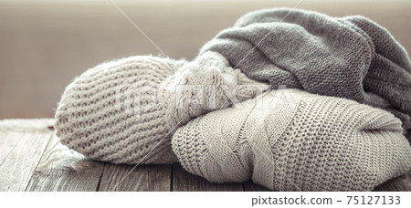 A cozy stack of knitted sweaters on a wooden background. 75127133