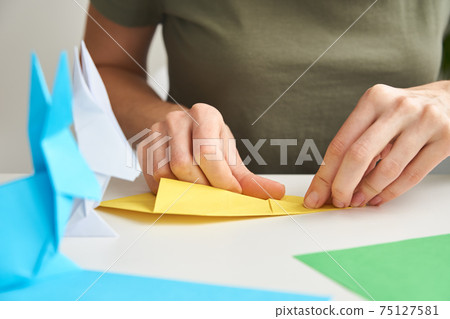 DIY concept. Woman make origami easter rabbit from color paper. Origami lessons DIY concept. Woman make origami easter rabbit from color paper. Origami lessons 75127581
