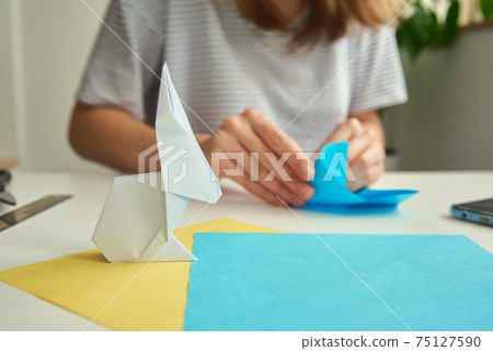 DIY concept. Woman make origami easter rabbit from color paper. Origami lessons DIY concept. Woman make origami easter rabbit from color paper. Origami lessons 75127590