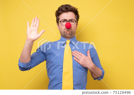 I swear. Funny young manwith red clown nose with hand on chest giving oath I swear. Funny young manwith red clown nose with hand on chest giving oath 75128496
