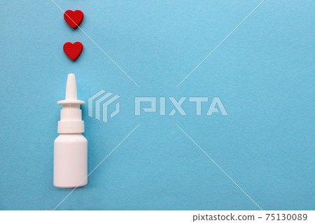 Two red hearts and a bottle of nasal spray on a blue background. Healthcare. Vasoconstrictors. 75130089