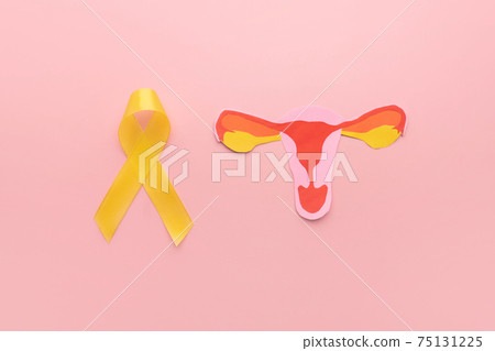 Yellow ribbon awareness with uterus shape made frome paper on pink background. Symbol of  National Endometriosis awareness month of March. Female reproductive health concept. 75131225