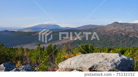 Autumn mountain landscape .Hill slope with coniferous thickets against the background of mountain ranges and blue sky. 75132152