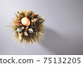 Easter eggs in a bouquet of dried flowers on a gray background. 75132205