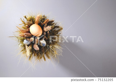 Easter eggs in a bouquet of dried flowers on a gray background. 75132205
