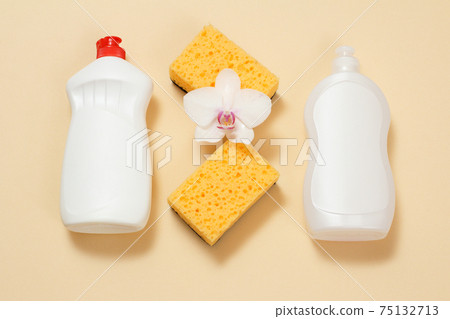 Bottles of dishwashing liquid and sponges on a beige background. 75132713