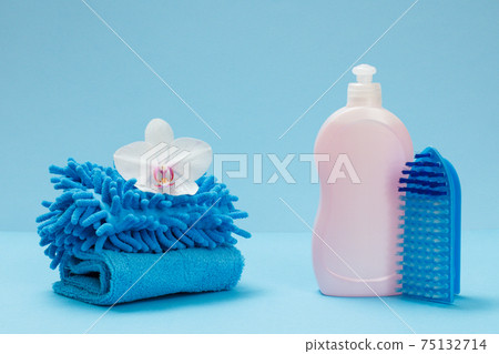 Bottle of detergent, a brush and rags on the blue background. 75132714