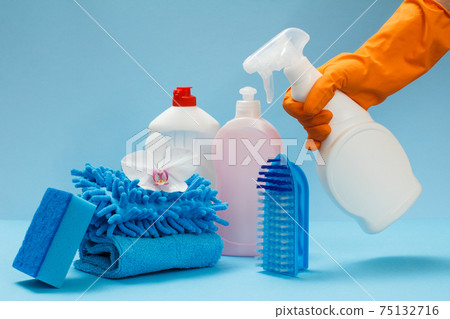 Woman's hand in protective glove with bottle of glass and tile cleaner on the blue background. Woman's hand in protective glove with bottle of glass and tile cleaner on the blue background. 75132716