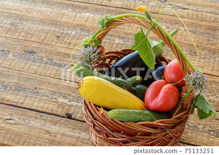 Just picked vegetables in wicker basket on old wooden boards. 75133251
