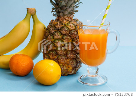 Fresh tropical fruits and a glass of juice on a blue background. Fresh tropical fruits and a glass of juice on a blue background. 75133768